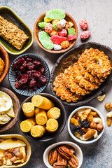 Variety of snacks and sweets on gray background. Waffles, nuts, sweets, cookies, chips and fruits, top view, flat lay.
