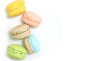 vertical line of colorful fresh sweet cake macarons on left size on white dish background, have copy space for put text.