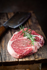 Raw fresh meat Ribeye Steak and seasonings on wooden background, rustic style