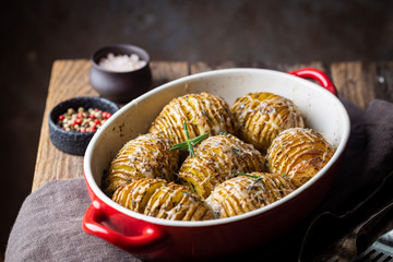 Baked hasselback potatoes with cheese, garlic and greens
