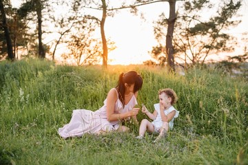 Mother and daughter having fun in the park. Happiness and harmony in family life. Beauty nature scene with family outdoor lifestyle.