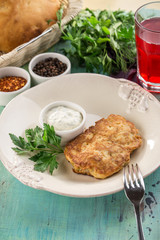 Fried pork chops in batter on white plate and glass of red drink on blue wooden table