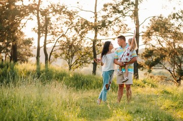 Happy family of three persons walking the grass in the park.