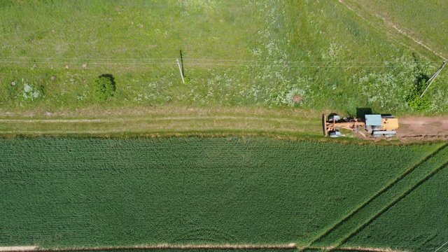 Tractor grader on farmland road at work, aerial view