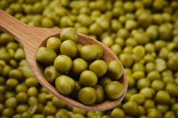 canned peas in wooden spoon closeup