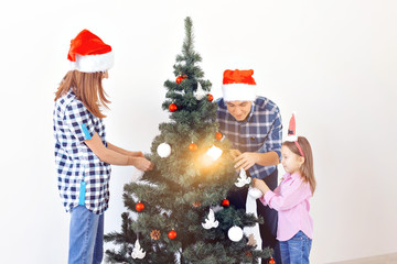 Holidays, x-mas and celebrating concept - Happy family decorating Christmas tree in holiday on white background