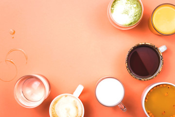 Different drinks cappuccino, tea, sea buckthorn juice, milk, water, orange juice and matcha on a bright coral pink background. Top view, flat lay, copy space.