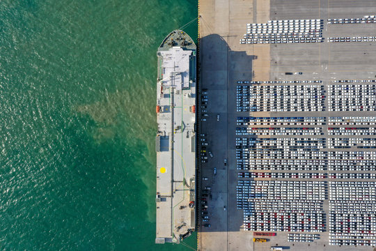 Aerial view of the huge ro-ro ship loading new cars. Automotive container carriers oversea services. Transportation business for prefabricated cars by sea freight