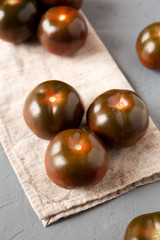 Kumato tomatoes on a gray surface, low angle view. Close-up.