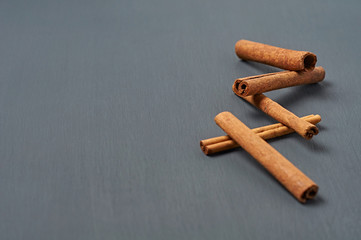 Heap of five flavour cinnamon sticks lies on dark scratched desk on kitchen. Space for text