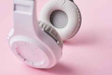 Closeup part of white wireless headphones on the pink background