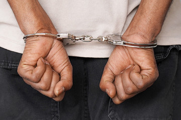 Close-up arrested hands african man handcuffed. Prisoner or arrested terrorist hands in handcuffs.  - obrazy, fototapety, plakaty