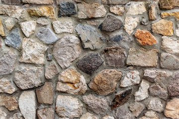 The wall of natural stone of gray and brown in the form of bricks with cement. Building from ecological material, construction background from rock texture close-up.