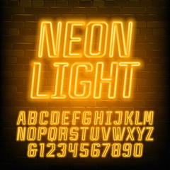 Naklejka na ściany i meble Neon alphabet font. Yellow neon geometric letters and numbers. Brick wall background. Stock vector typescript for your typography design.