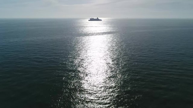 Aerial bird view footage of large ship moving over ocean in sun reflection quiet sea beautiful weather ships have been important contributors to human migration and commerce 4k high resolution