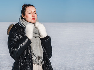 Happy, young woman on a background of a snowy field on a clear, sunny day