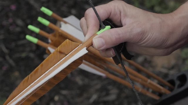 A close-up of a lady archer knocks her arrow to her bow preparing to shoot a target. One of a series of twelve shots.