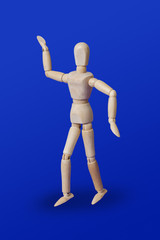 Dancing wooden toy figure on blue
