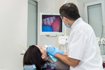 Obraz premium Dentist checking patient's teeth with camera, looking on screen