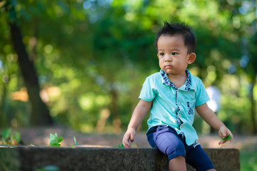 Asian child boy playing on green grass in city park morning light