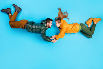 Top above high angle view full length body size photo of cheerful positive couple falling down lying holding hands smiling toothily isolated pastel blue color background © deagreez