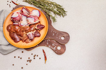 Fresh raw duck offal: heart, liver, stomach. Dry spices, salt, chili pepper. Wooden cutting boards, stone concrete background