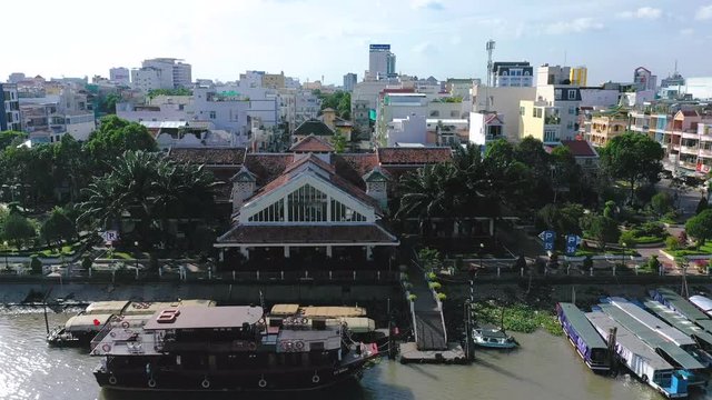 The city of Can Tho, Vietnam featuring boats, river, and architecture from drone on a sunny afternoon. Camera flies in from river to close up of roof of French Colonial Building