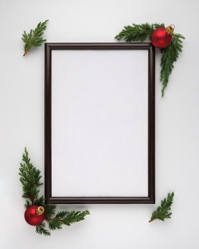Christmas or New Year composition. Photo frame with copy space, Christmas tree branches and Christmas balls on white background. Flat lay, top view, vertical layout