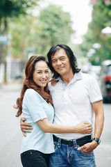 Obraz premium Happy mature couple in love hugging in the street and looking at camera