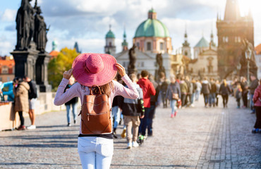 Touristin mit rotem Hut steht auf der berühmten Karlsbrücke in Prag während eines Sightseeing...