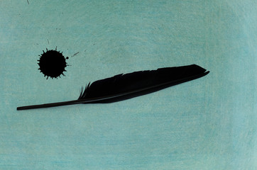 ink and black feather on ancient turquoise background - text space