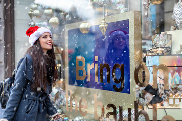 Frau mit Nikolaus Mütze betrachtet ein Schaufester beim Einkaufsbummel zu Weihnachten