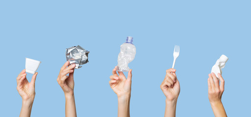 Hands holding trash on a light blue background. The concept of separate trash, stop plastic,...