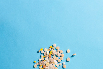 A lot of pills of different types on a blue background. Insomnia, taking pills according to the regimen, vitamins. Flat lay, top view