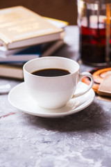 Cup of coffee and stack of book on a table.