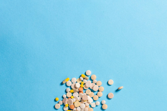 A lot of pills of different types on a blue background. Insomnia, taking pills according to the regimen, vitamins. Flat lay, top view