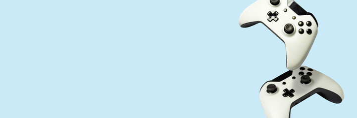 Flying air gamepads from a game console on a blue background. The concept of games, online games, e-sports. Levitation. Banner © Alex