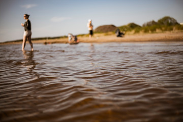 Small vawes of baltic sea. Patterns of water and light. people in background having fun