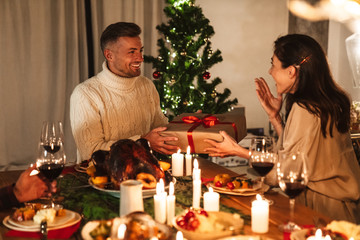 Photo of nice delighted couple smiling and giving presents