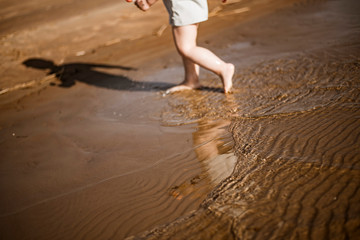 Small vawes of baltic sea. Patterns of water and light. People in background. Kid walking in water. 