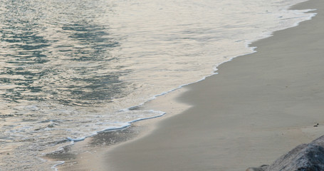 Sea wave on beach at sunset