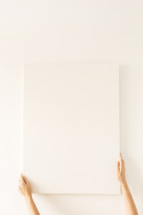 Female hands hold blank canvas with empty mockup copy space. Minimal art concept.