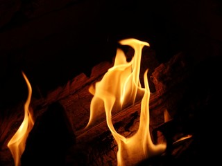 Flames burn from logs in a fireplace, dark background
