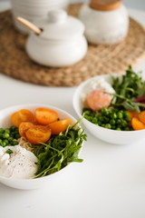 Salad with tomatoes, arugula, green peas and poached egg. A delicious and healthy lunch for two.