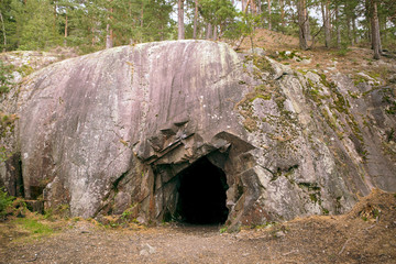 Rock wall with a dark hole, entrance to the cave in Spro, Mineral historic mine. Nesodden Norway. Nesoddtangen peninsula.