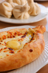 Home Georgian cuisine in a restaurant: Khachapuri Adjarian and Khinkali
