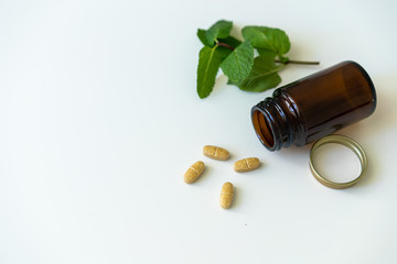 Nature health and medicine concept photo with copy space on left side, bottle with pills and fresh mint leaf.