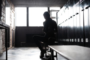 Caucasian female athlete preparing for a workout in a gym locker room.