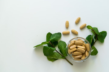 Nature health concept photo with organic pills and green herbs around.