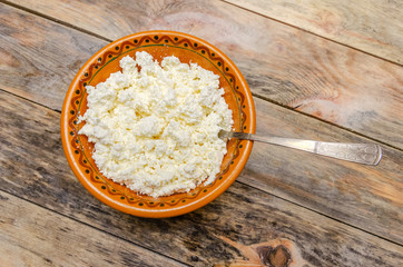 Cottage cheese in a brown bowl on a wooden background. Healthy Breakfast, top view